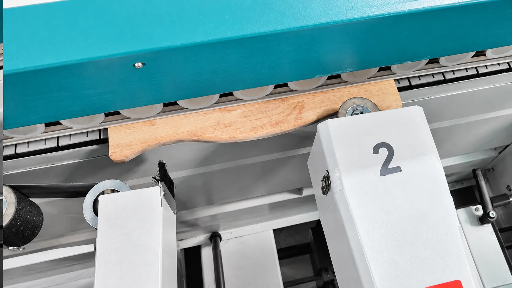 Servo contour sanding head finishing a shaped wooden workpiece under hold-down rollers