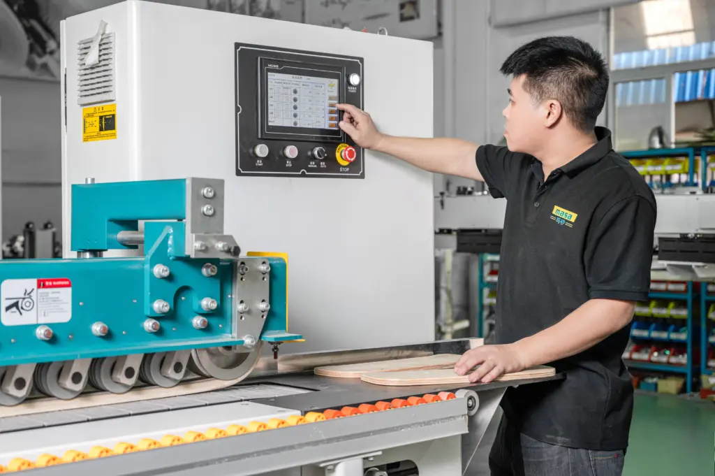 Factory worker in black shirt operating touchscreen control panel of large industrial woodworking machine
