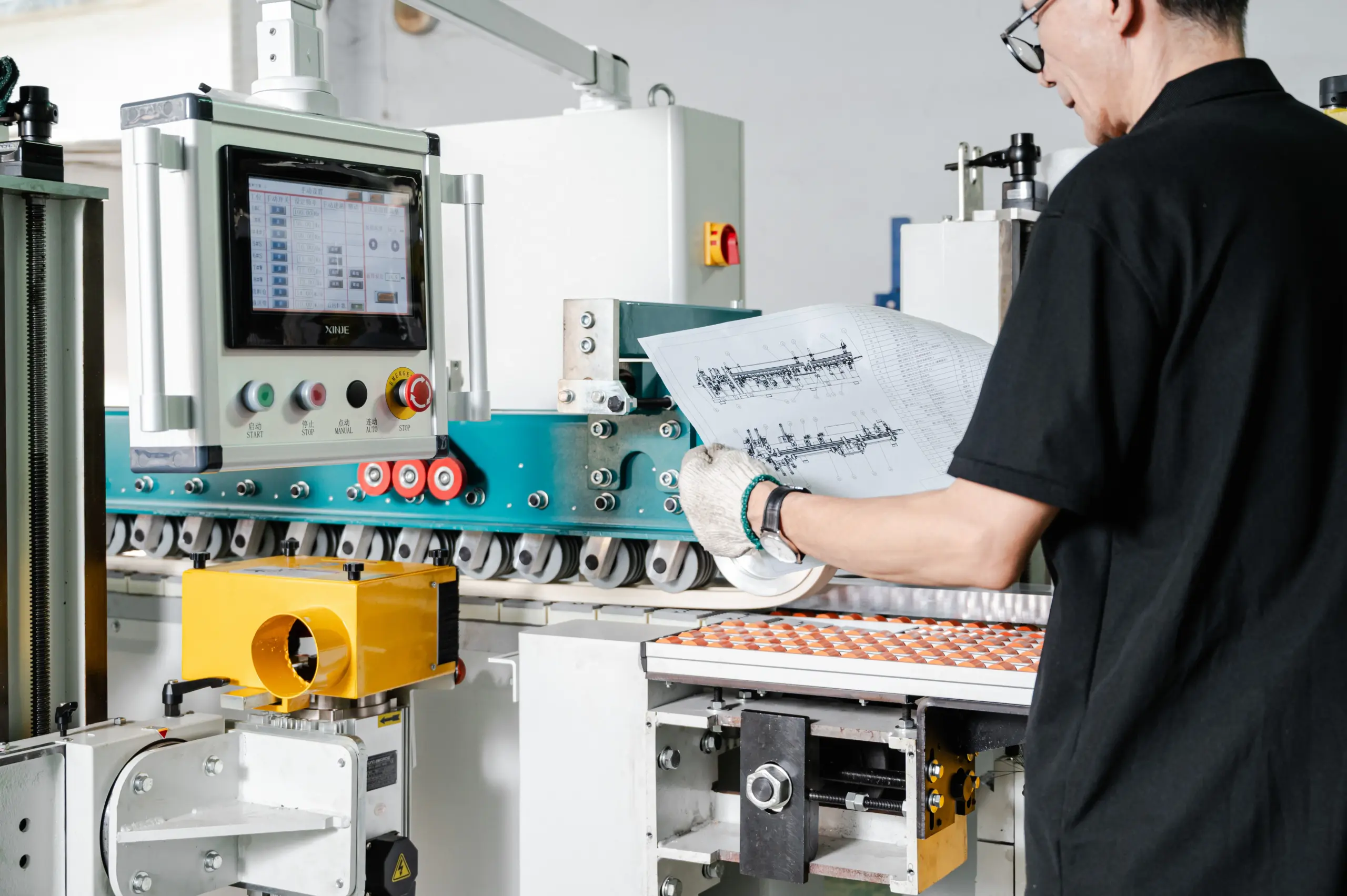 Operator checking a sanding-machine drawing against the HMI and feed section during setup
