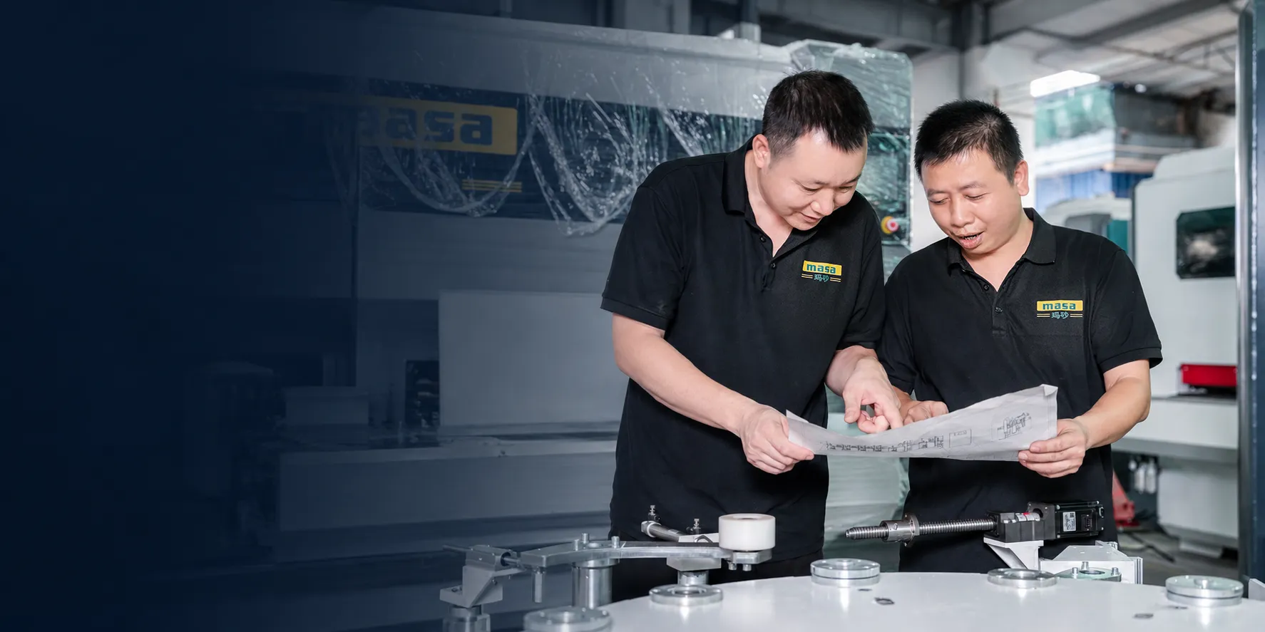 MASA engineers reviewing a machine drawing on the factory floor