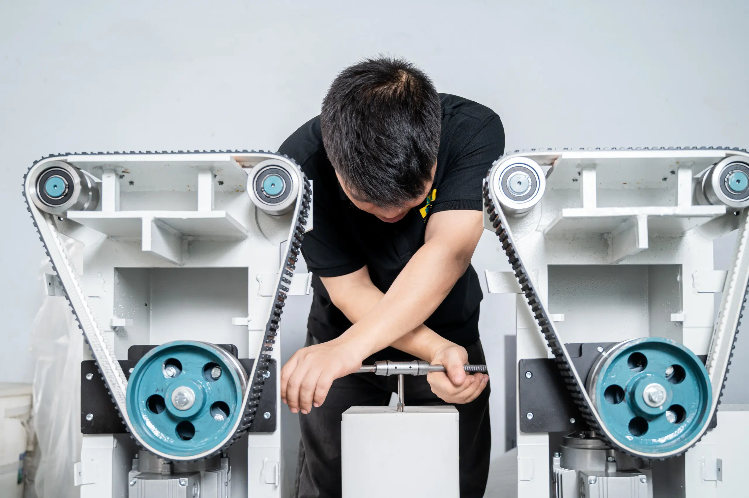 Technician assembling triangular belt-drive sanding units during custom machine build